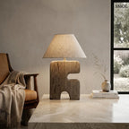 Absztrakt, tömör fából faragott asztali lámpa világos bézs vászon lámpabúrával, nappaliban, dohányzóasztalon