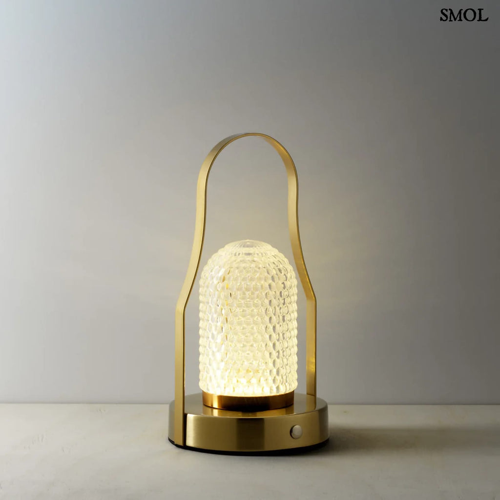 Hordozható LED asztali lámpa arany (brass) színű vázzal és fogantyúval, valamint texturált üveg búrával, meleg fénnyel