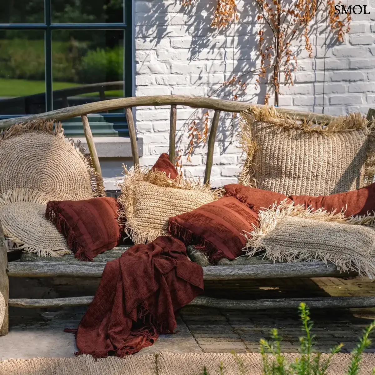 Hosszúkás bordó bársony díszpárnahuzat rojtokkal és csíkos textúrával, teraszon, kanapén