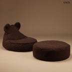 Barna színű, puha teddy anyagú gyerek babzsákfotel mackófülekkel, settben, barna háttérrel