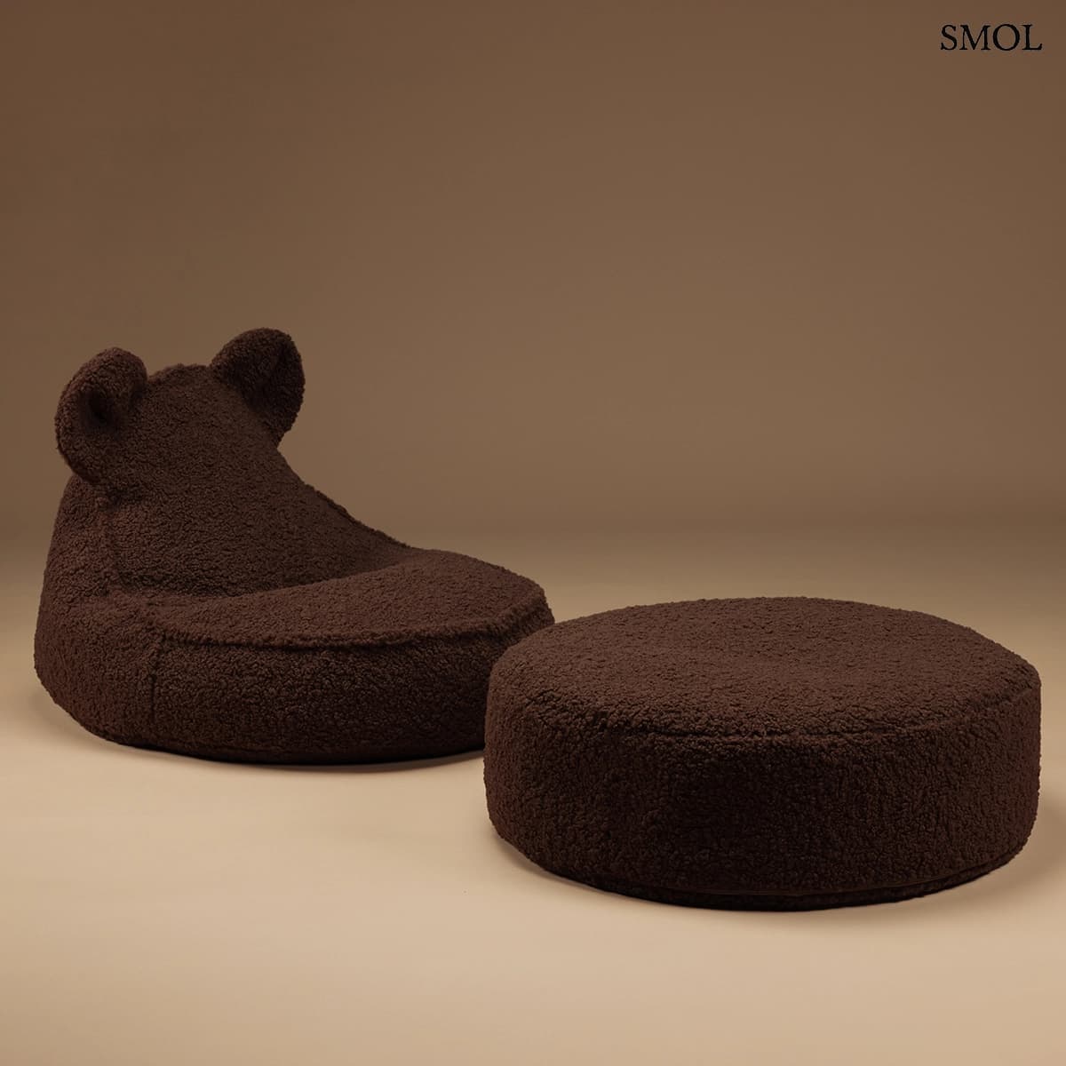 Barna színű, puha teddy anyagú gyerek babzsákfotel mackófülekkel, settben, barna háttérrel