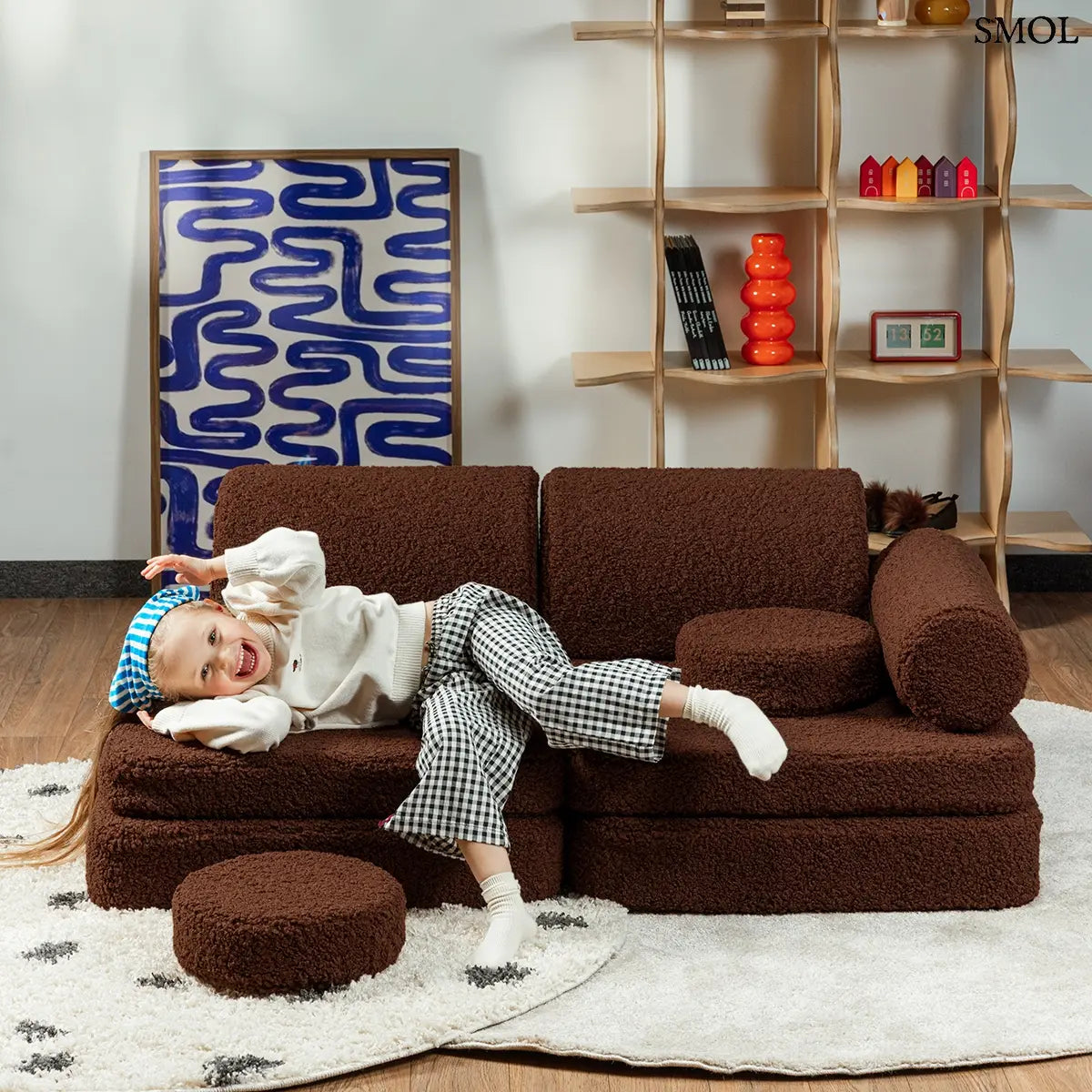 Barna, bársonyos tapintású kilencrészes gyerekkanapé henger és kerek párnákkal, puha teddy szövet borítással, gyerekszobában, gyerekkel