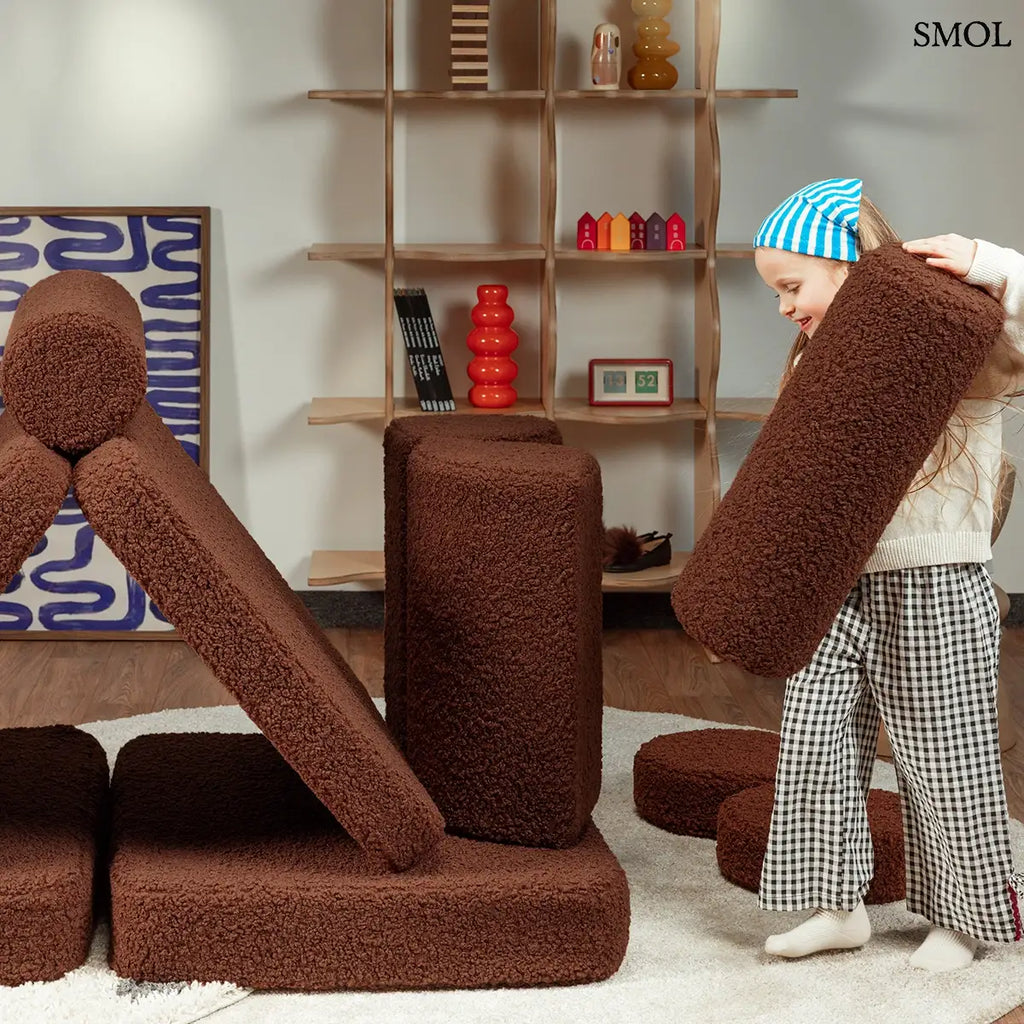 Barna, bársonyos tapintású kilencrészes gyerekkanapé henger és kerek párnákkal, puha teddy szövet borítással, elemekkel játszó gyerekkel
