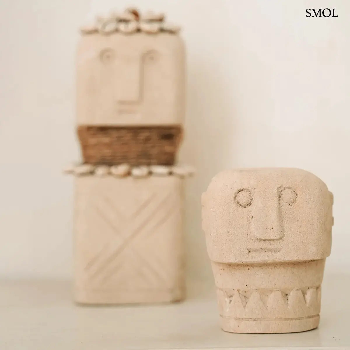 Natúr homokkő sumba szobor arcmintával, kézzel faragott, 10×9 cm, kagylós szoborral a háttérben
