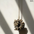 Barna kagyló függődísz, kézműves bojt formában, natúr kötélre akasztva falnál