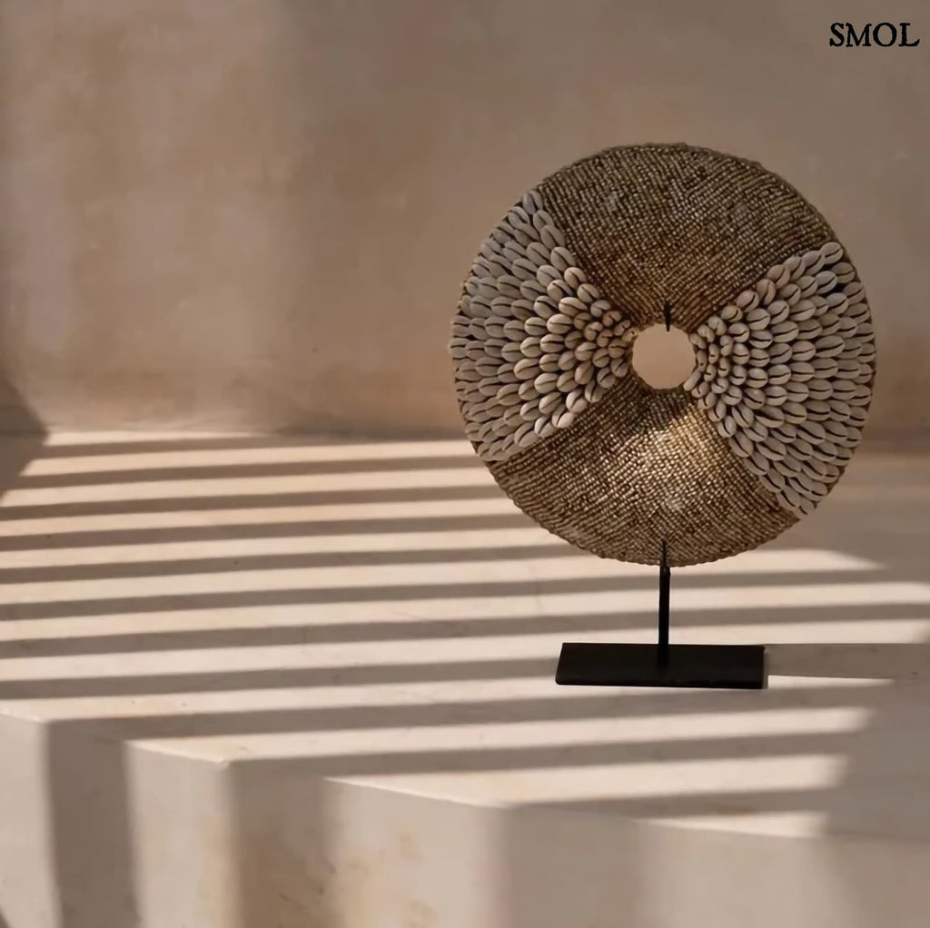 Natúr fehér kagylókból készült, kör alakú kagyló dekoráció fekete fémállvánnyal natúr háttérrel