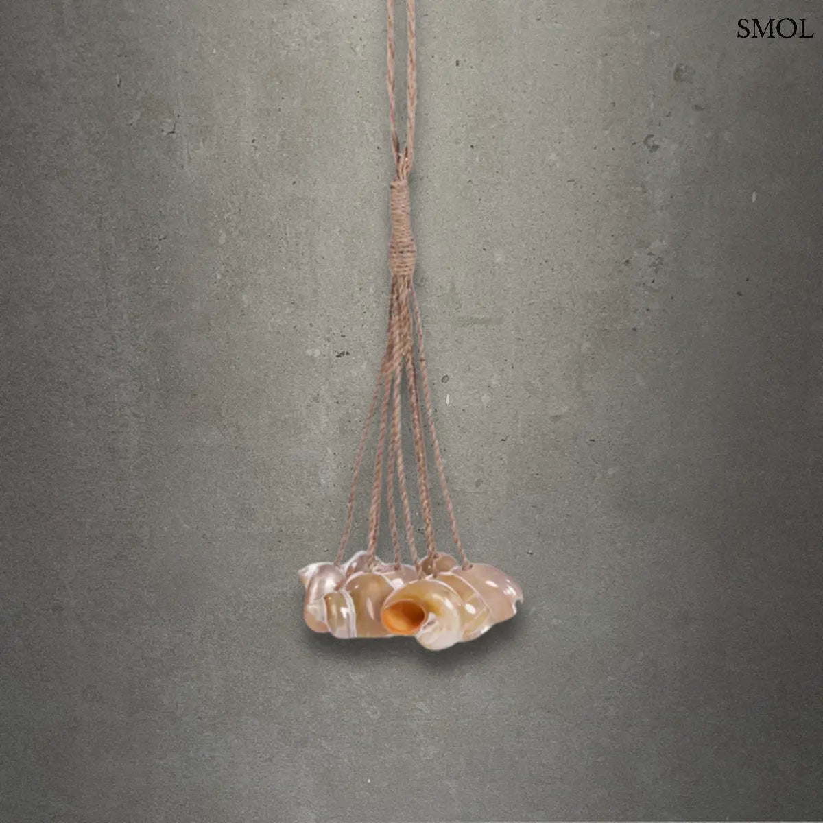 Kézzel készített kagylós dekoráció natúr kötélen függő conch kagylókkal, szürke háttérrel