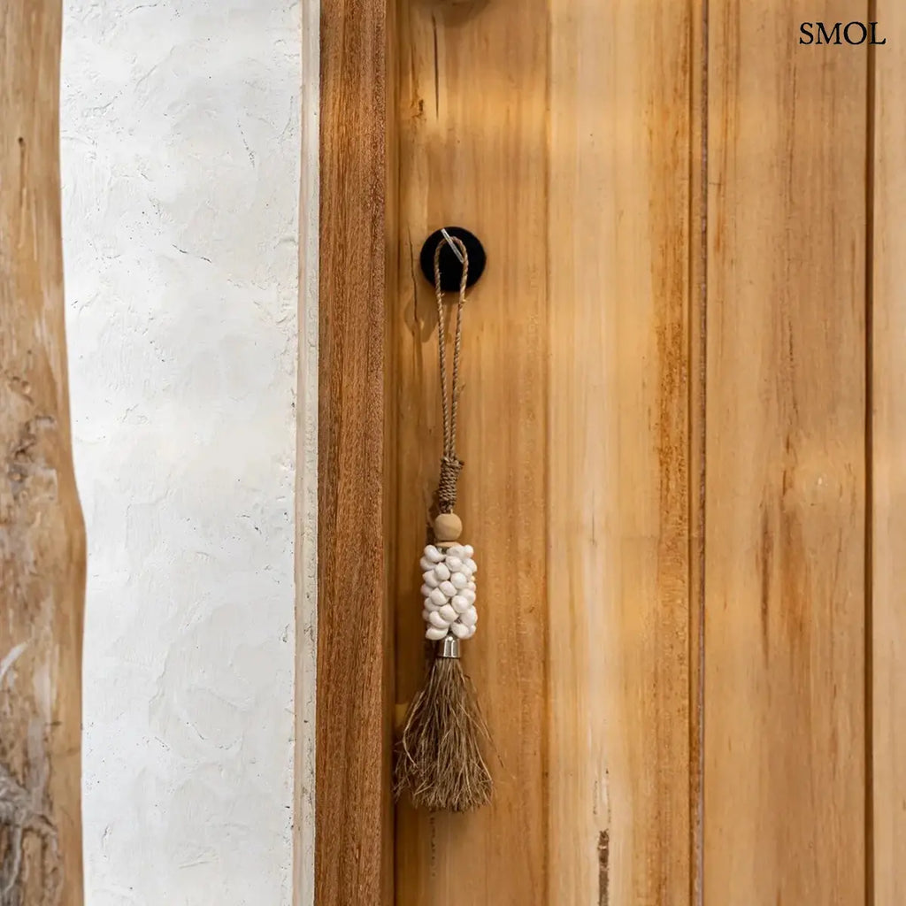 Kézzel készült kagylós dekoráció natúr raffia bojttal és kauri kagylókkal, kilincsen