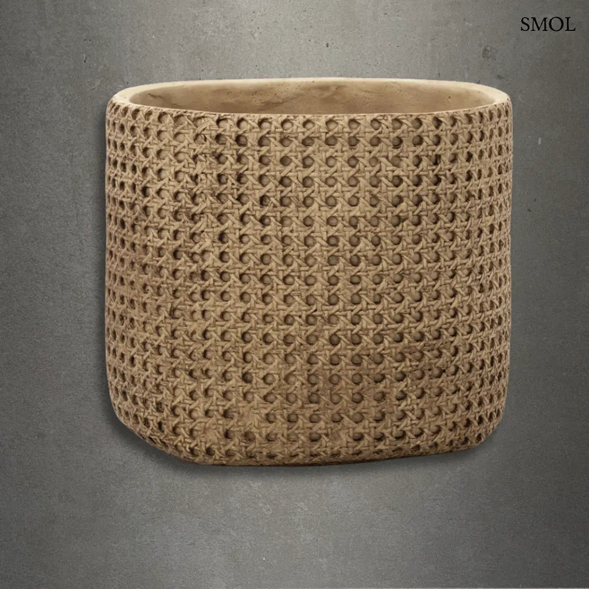 Natúr színű, henger alakú beton kaspó rattan hatású fonott mintával, szürke háttérrel