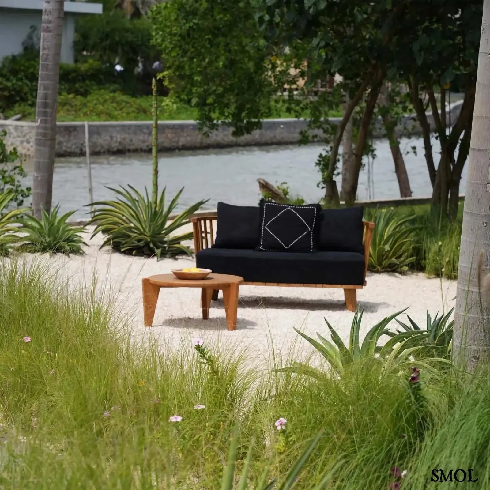 Kétszemélyes kanapé, újrahasznosított tíkfa kerettel és fekete kárpit párnákkal, kertben, párnával