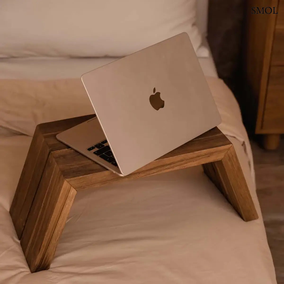 Tömör teakfa laptopasztal szögletes formával, natúr, 55×22 cm, félig kinyitott laptoppal, ágyon