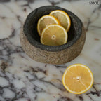 Rusztikus fekete lávakő tál kívül durva, belül csiszolt textúrával, természetes vulkanikus kőből, citrommal