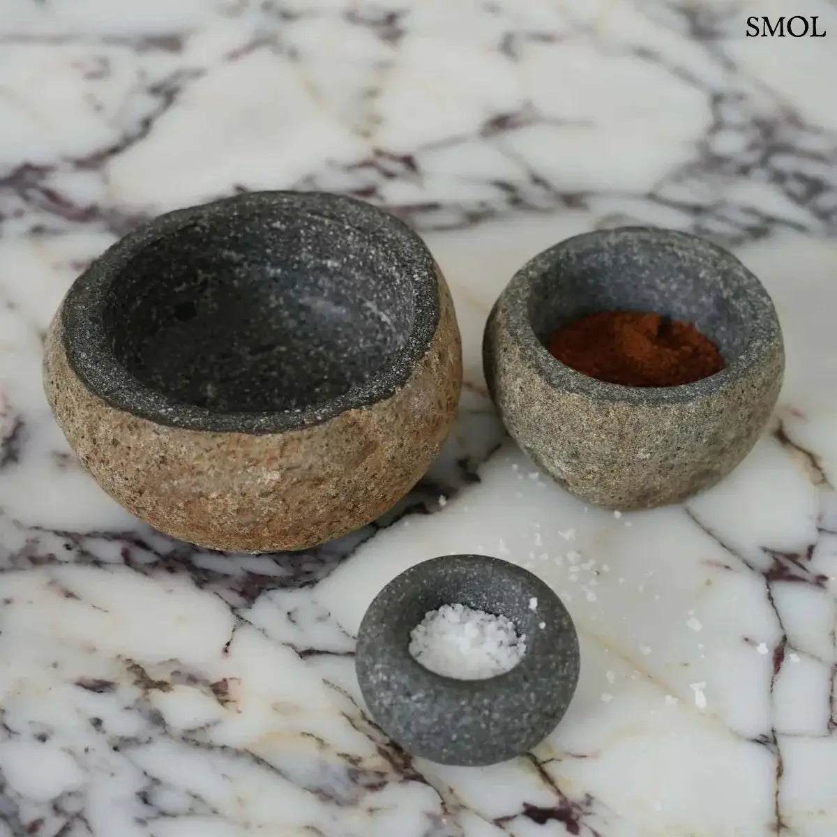 Rusztikus fekete lávakő tál kívül durva, belül csiszolt textúrával, természetes vulkanikus kőből, két méretben márványon