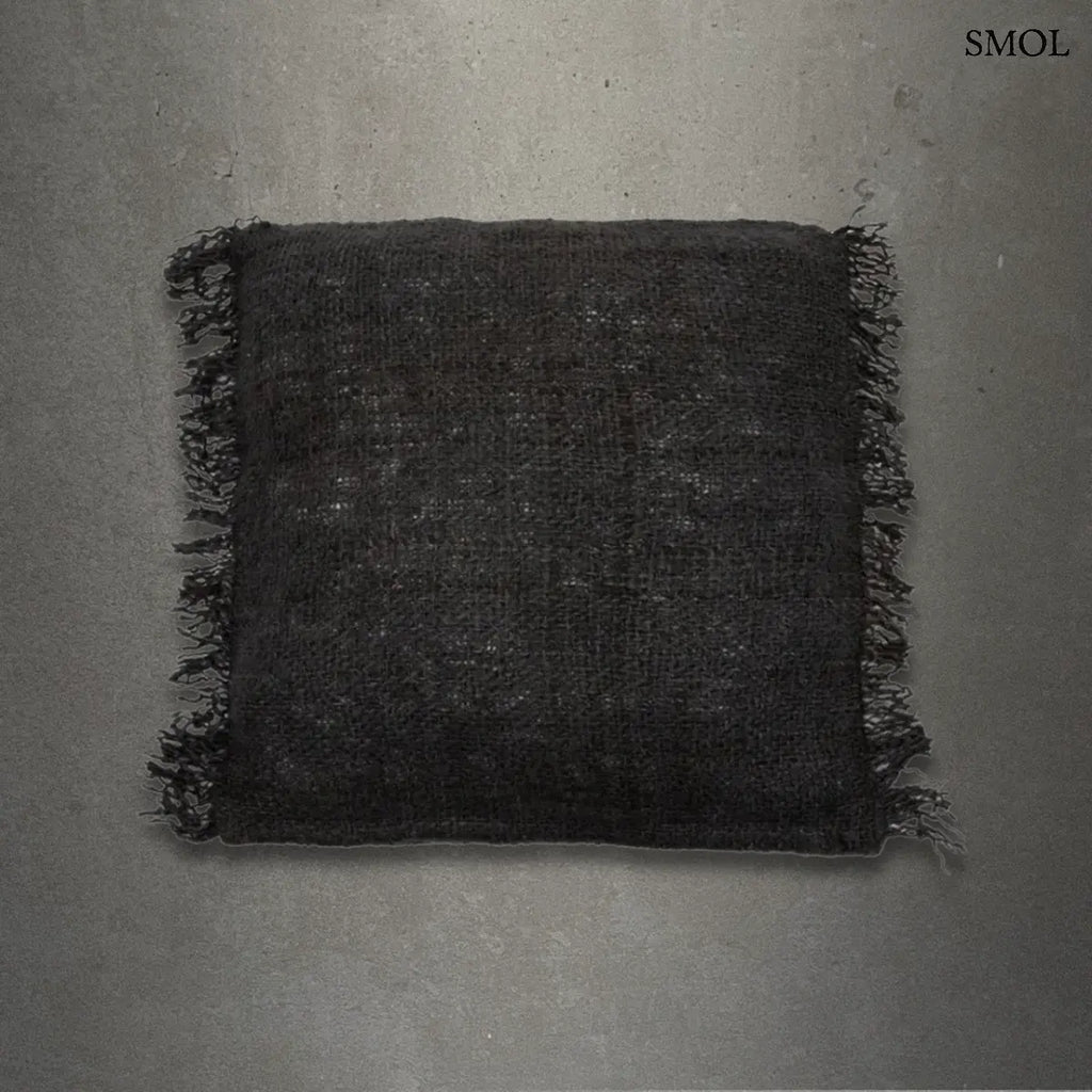 Éjfekete, rojtos szélű, rusztikus szövésű pamut díszpárnahuzat, szürke háttérrel