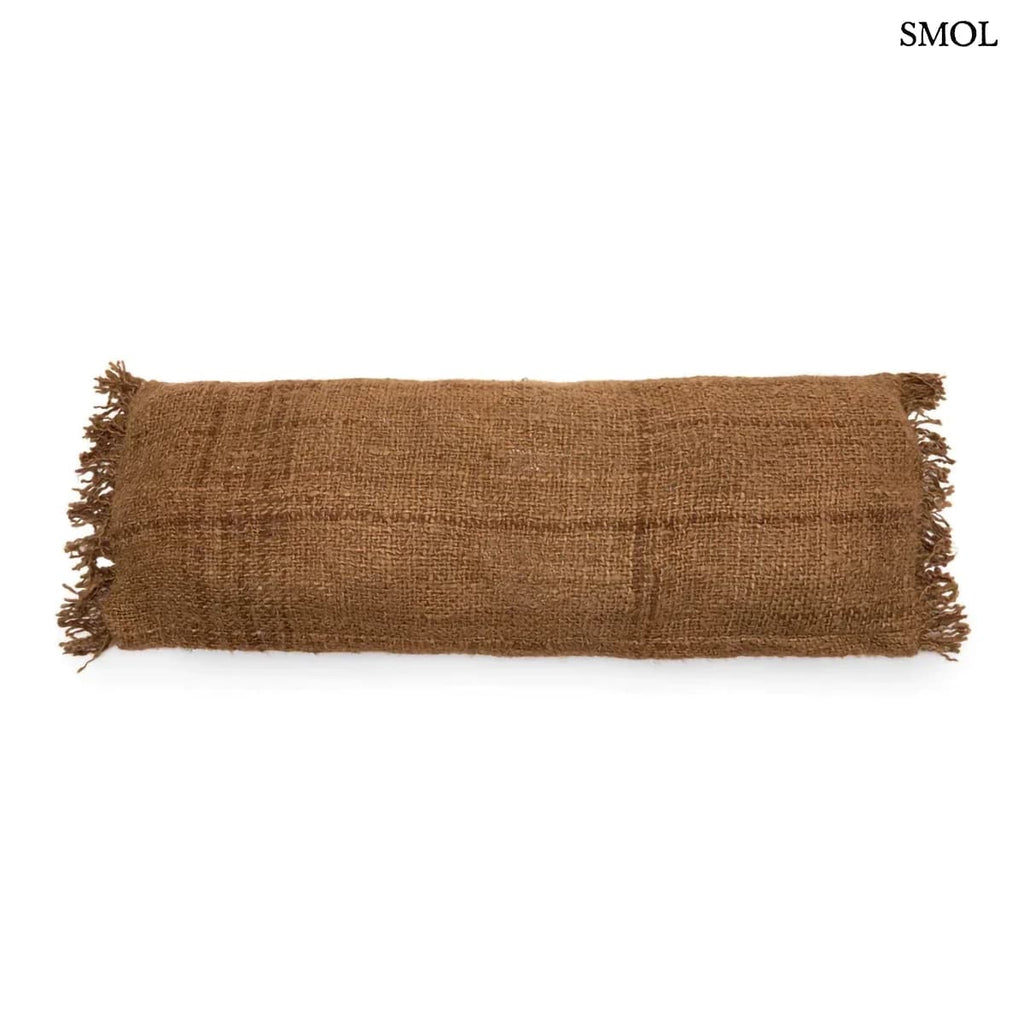 Hosszúkás, barna színű pamut díszpárnahuzat rojtos szélekkel és rusztikus szövéssel, fehér háttérrel