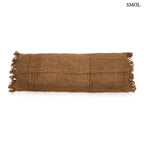 Hosszúkás, barna színű pamut díszpárnahuzat rojtos szélekkel és rusztikus szövéssel, fehér háttérrel