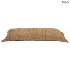 Hosszúkás, barna színű pamut díszpárnahuzat rojtos szélekkel és rusztikus szövéssel, fektetve, oldalról