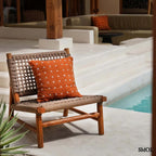 Pamut díszpárnahuzat, élénk terrakotta színben, sűrűn elhelyezett, kézzel varrott fehér kereszt mintákkal, teraszon, fotelben