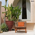 Pamut díszpárnahuzat, élénk terrakotta színben, sűrűn elhelyezett, kézzel varrott fehér kereszt mintákkal, kertben, ablak előtt