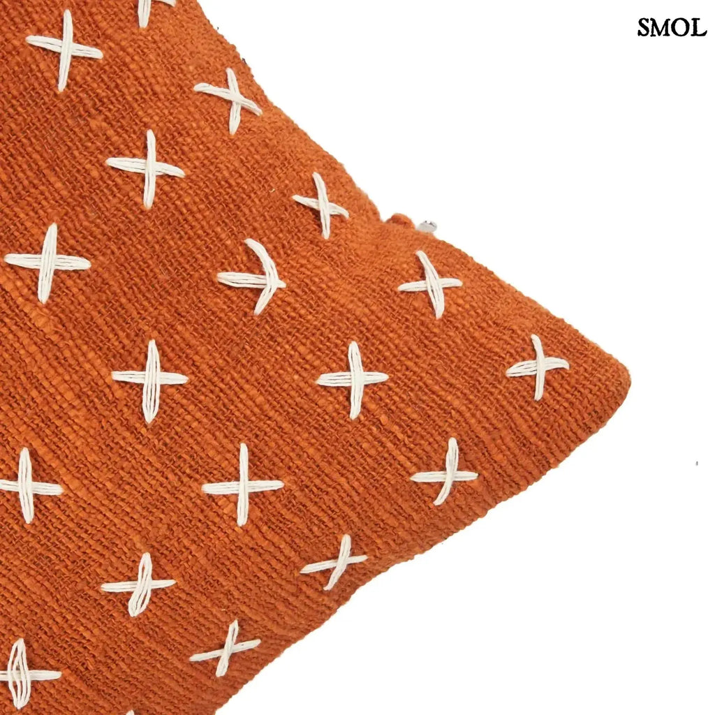 Pamut díszpárnahuzat, élénk terrakotta színben, sűrűn elhelyezett, kézzel varrott fehér kereszt mintákkal, sarok nagyítva