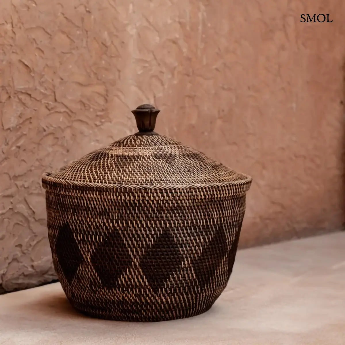 Natúr barna rattan tárolókosár fedővel és faragott fa fogantyúval, 55×52 cm, barna háttérrel