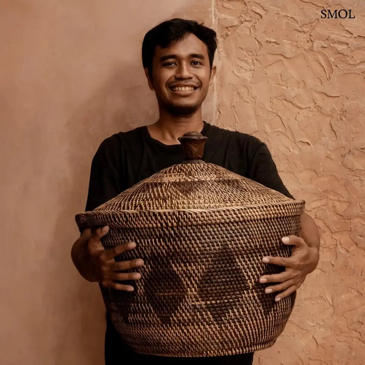 Natúr barna rattan tárolókosár fedővel és faragott fa fogantyúval, 55×52 cm, férfi karjaiban