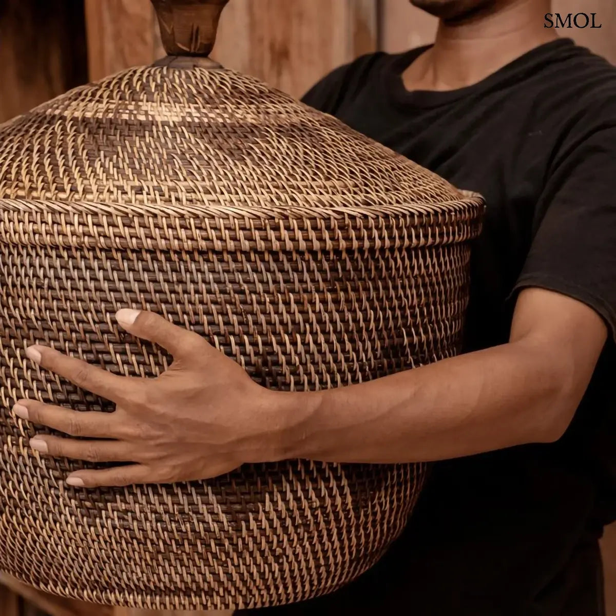 Natúr barna rattan tárolókosár fedővel és faragott fa fogantyúval, 55×52 cm, férfi kezében, oldalról