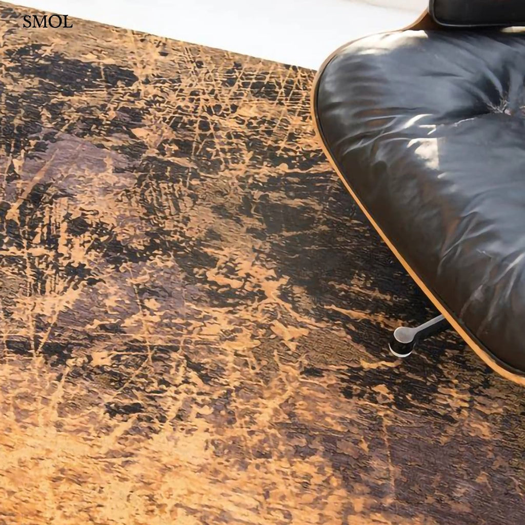 ECO RUG DEEP MINE absztrakt szőnyeg arany-barna kombinációban, négyzet alakú, repedezett, karcos felülettel, fotellel nagyítva