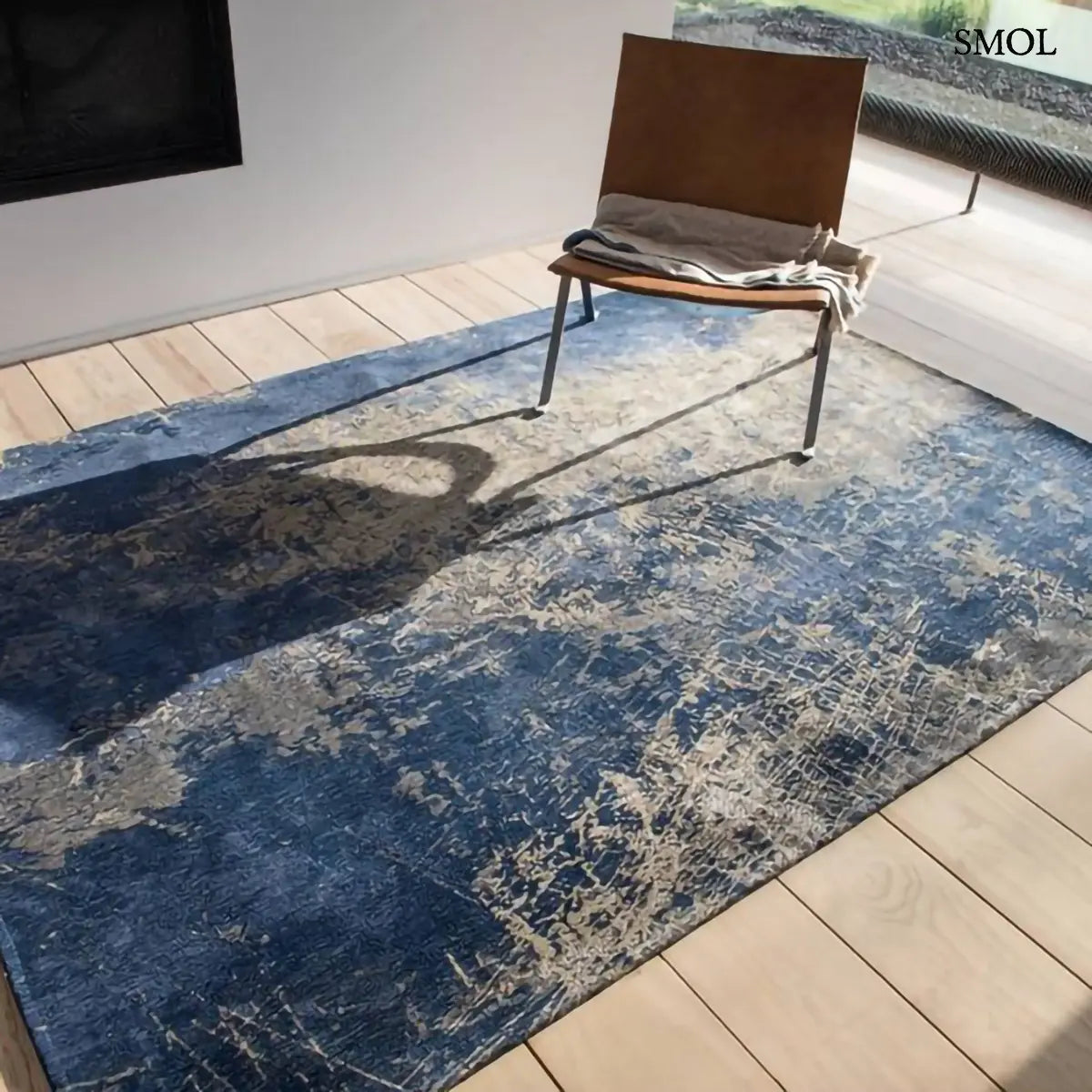 ECO RUG ABYSS BLUE absztrakt szőnyeg mélykék-arany kombinációban, repedezett, karcos felülettel, újrahasznosított poliészter, bőr fotellel, takaróval, ferdén