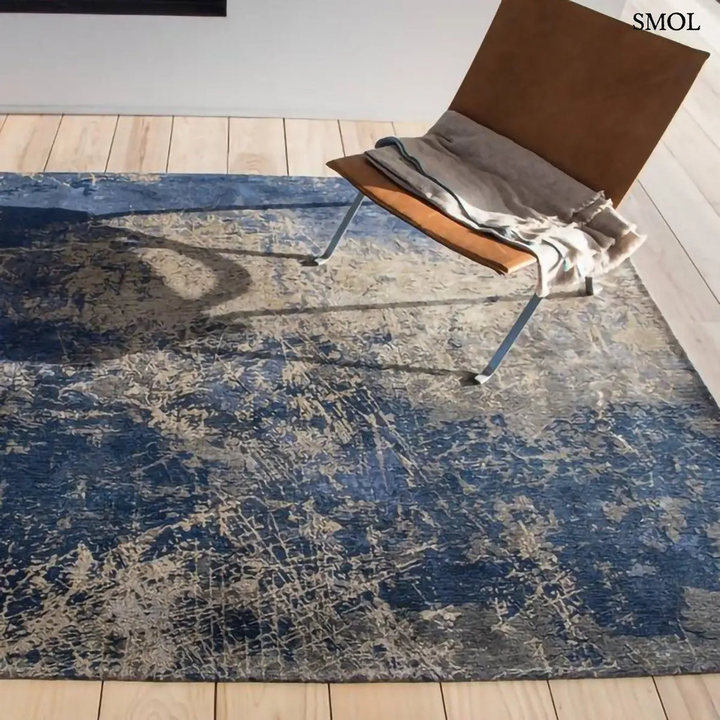 ECO RUG ABYSS BLUE absztrakt szőnyeg mélykék-arany kombinációban, repedezett, karcos felülettel, újrahasznosított poliészter, fotellel, felülről