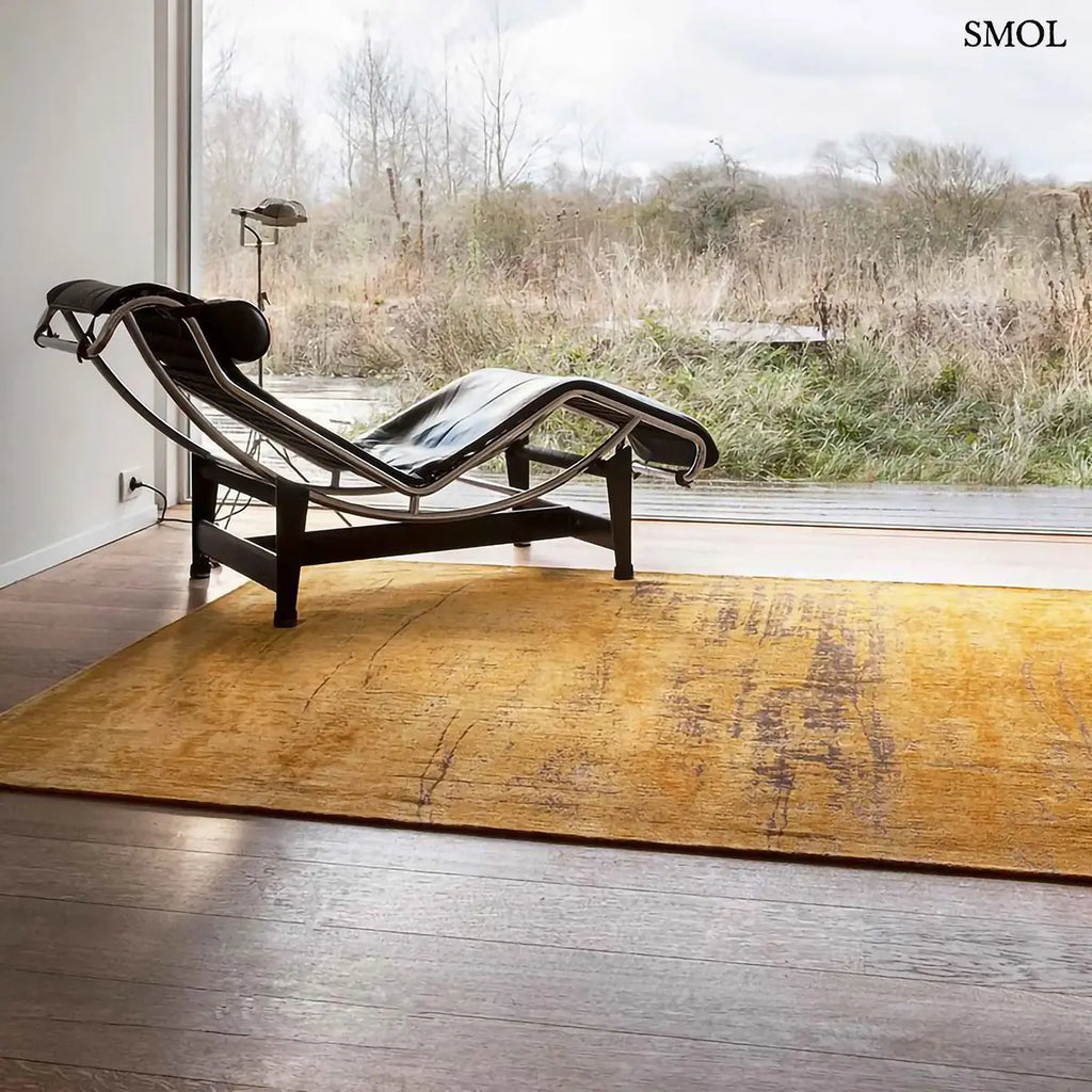 ECO RUG LIBERTY GOLD szőnyeg, aranyszín alapon sötétbarna és fekete festékszerű vonalakkal, action painting hatású mintázattal, fotelle, terasz előtt