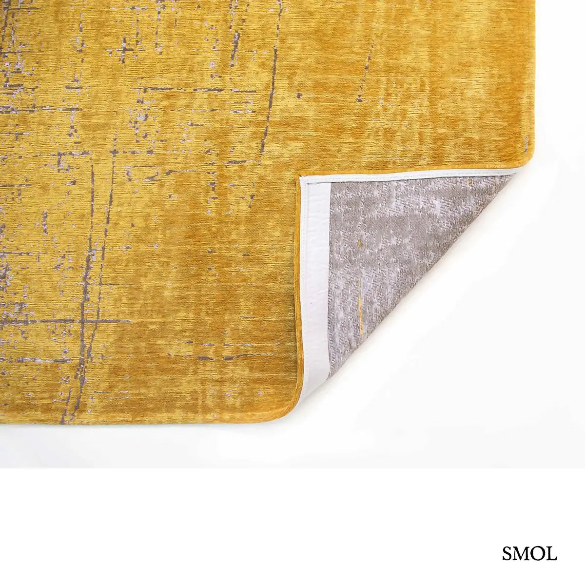 ECO RUG LIBERTY GOLD szőnyeg, aranyszín alapon sötétbarna és fekete festékszerű vonalakkal, action painting hatású mintázattal, felhajtott sarokkal, alulról