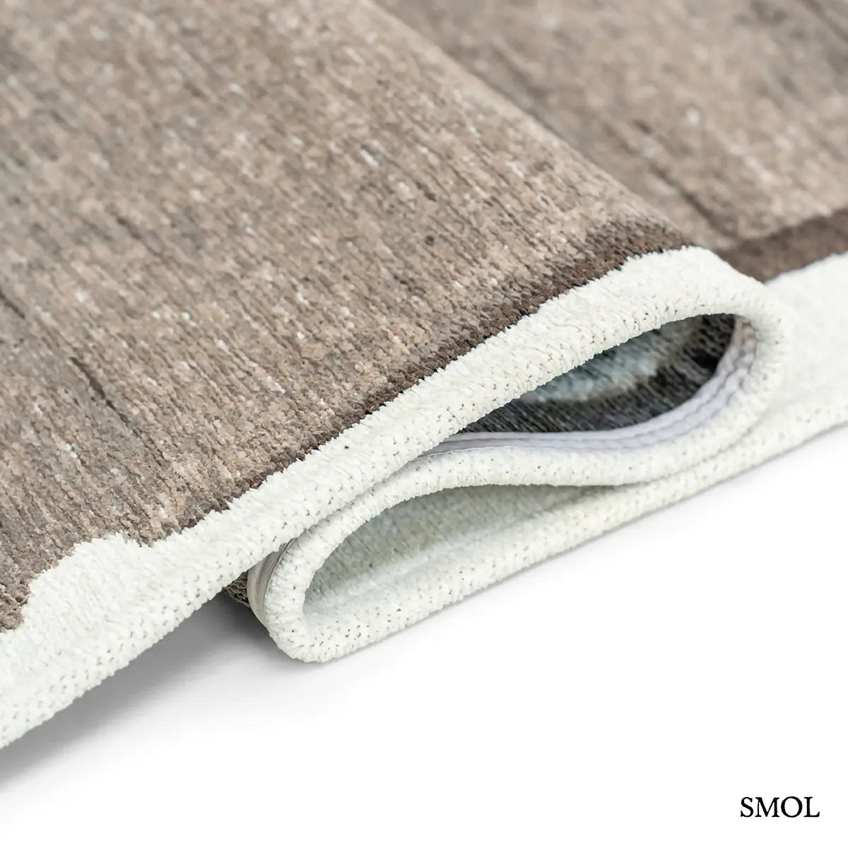 ECO RUG MASTIC absztrakt szőnyeg fehér alapon taupe-barna vízszintes rétegű festői mintával, hullámosra hajtogatva