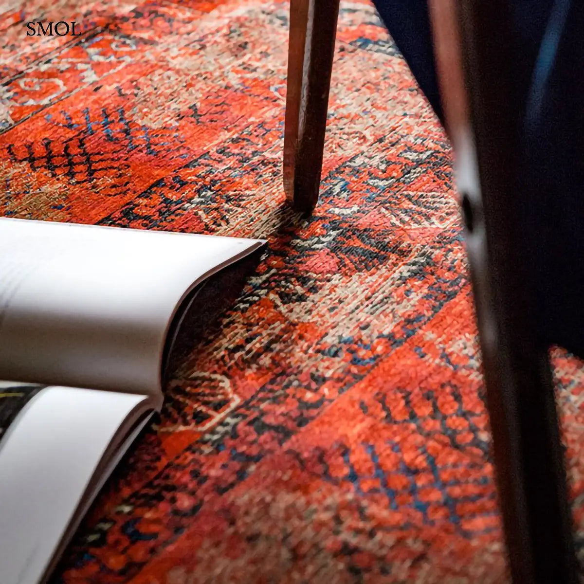 ECO RUG RED BRICK afgán mintás szőnyeg téglavörös alapon sötétkék Hadschlu mintával, koptatott vintage hatással, nyitott könyvvel, nagyítva