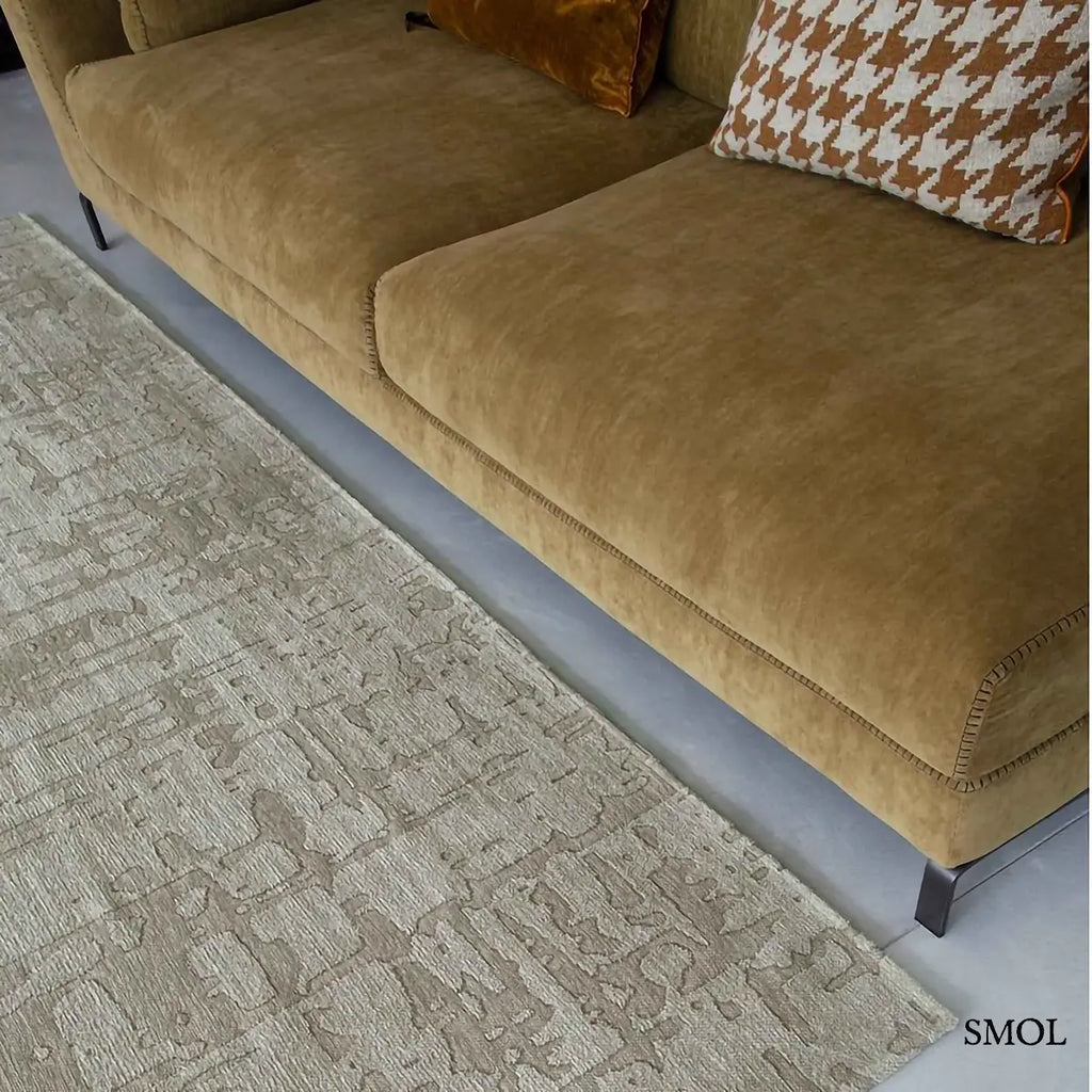 ECO RUG DRY BEIGE baobab mintás szőnyeg bézs-szürke tónusokban, halvány kéregszerű afrikai textúrával, kanapéval nagyítva