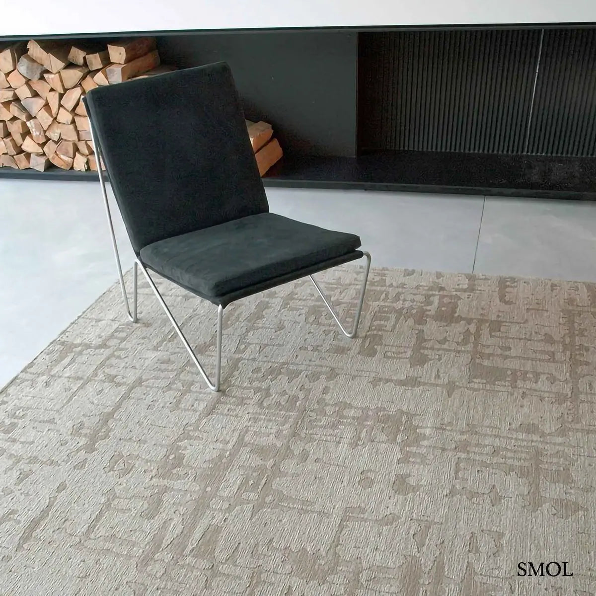 ECO RUG DRY BEIGE baobab mintás szőnyeg bézs-szürke tónusokban, halvány kéregszerű afrikai textúrával, fekete fotellel