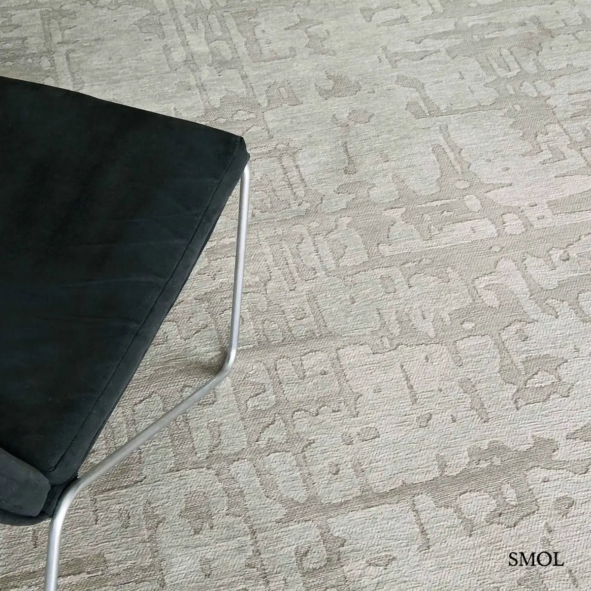 ECO RUG DRY BEIGE baobab mintás szőnyeg bézs-szürke tónusokban, halvány kéregszerű afrikai textúrával, fotellel, nagyítva