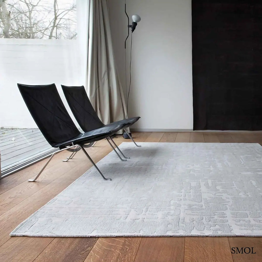 ECO RUG TSINGY OYSTER baobab mintás szőnyeg ezüstszürke tónusokban, halvány kéregszerű afrikai textúrával, nappaliban, fotelekkel