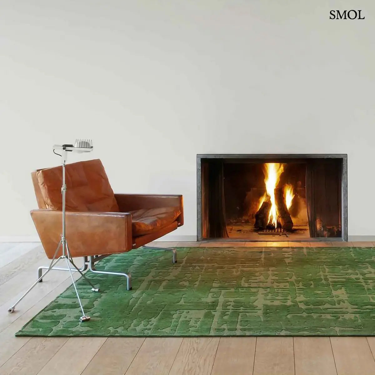 ECO RUG PERRIER'S GREEN szőnyeg, zöld alapon halványabb, repedezett baobab mintázattal, szabálytalan vonalvezetéssel, kandallóval és fotellel nappaliban