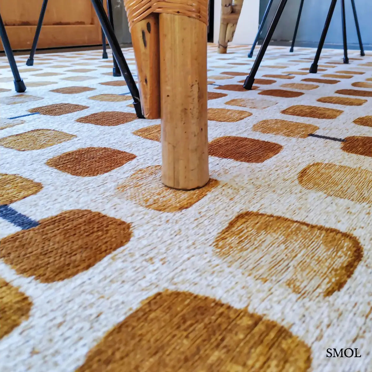 ECO RUG PEACH PARTY geometrikus szőnyeg arany-krém kombinációban, kerekített négyzetes mintával, fekete akcentusokkal, étkezőben, asztal alatt nagyítva