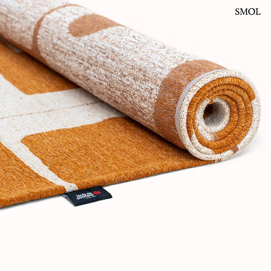 ECO RUG CURRY szőnyeg, törtfehér alapon barna-arany geometrikus formákból összeálló mozaikszerű mintázattal, feltekerve