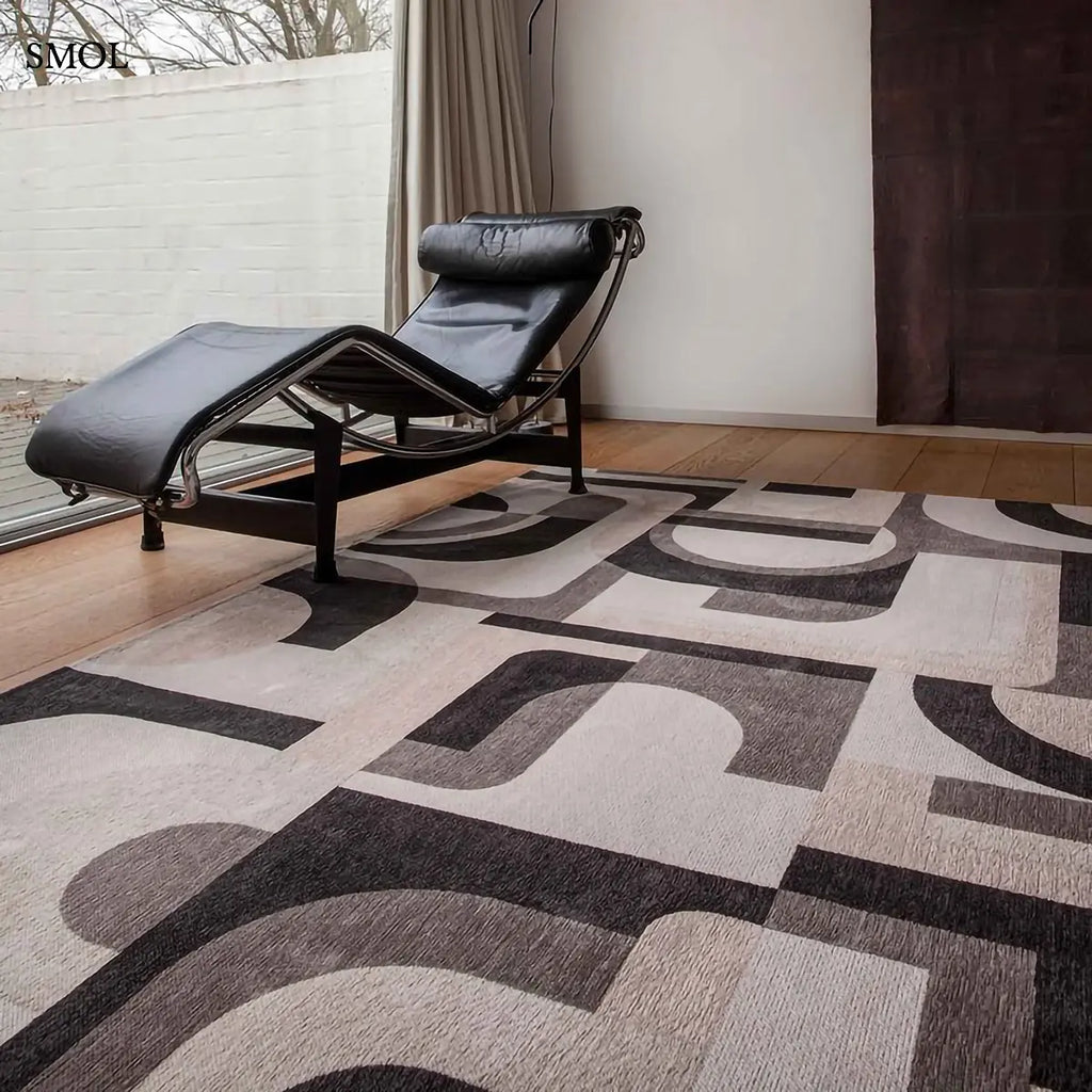 ECO RUG SAXON BEIGE szőnyeg, bézs és sötétszürke geometrikus formákból összeálló, íves-szögletes mintázattal, fekvő fotellel, szobában