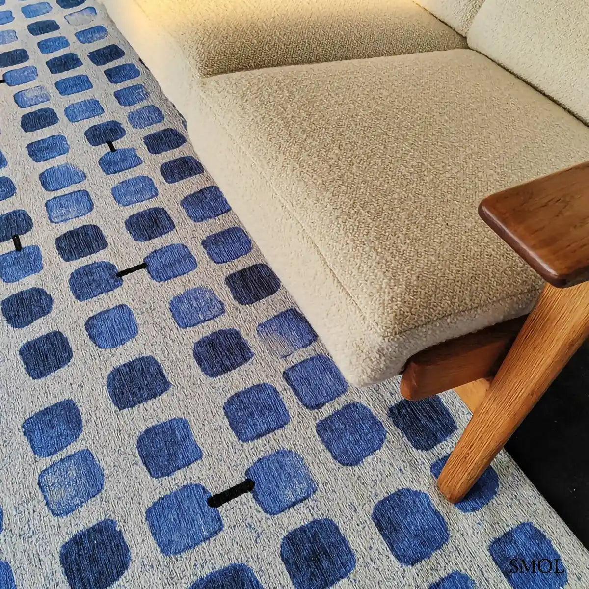 ECO RUG AMPARO BLUES geometrikus szőnyeg kék-fehér kombinációban, kerekített négyzetes mintával, fekete akcentusokkal, krémszínű kanapéval