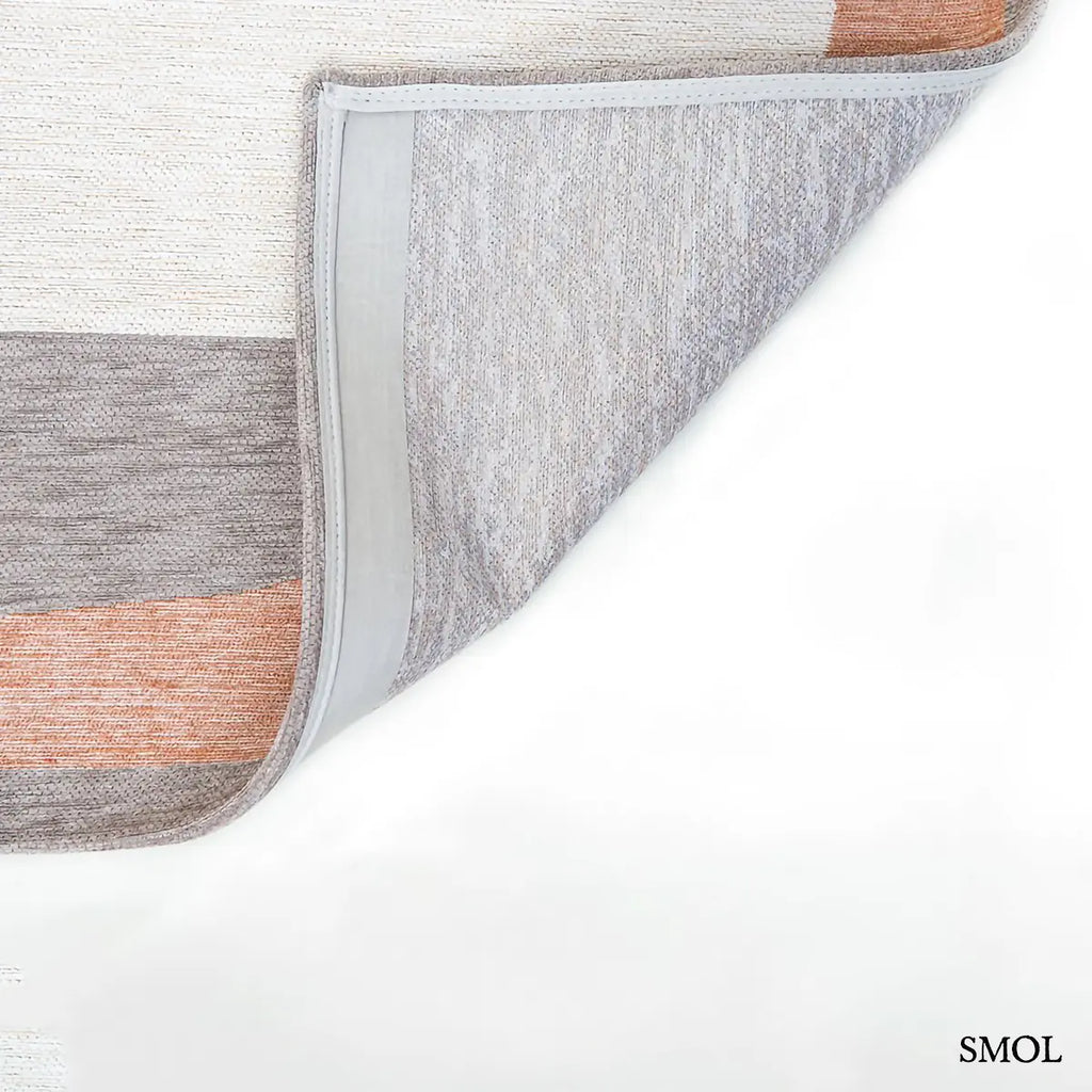 ECO RUG SECRET szőnyeg, narancs, kék, szürke és bézs geometrikus formákból összeálló, egymásba fonódó mintázattal, felhajtott sarokkal, alulról