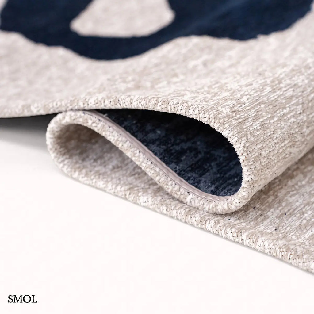 ECO RUG SEA INK kalligráfia mintás szőnyeg krém alapon sötétkék táncoló vonalakkal, hullámosra hajtva