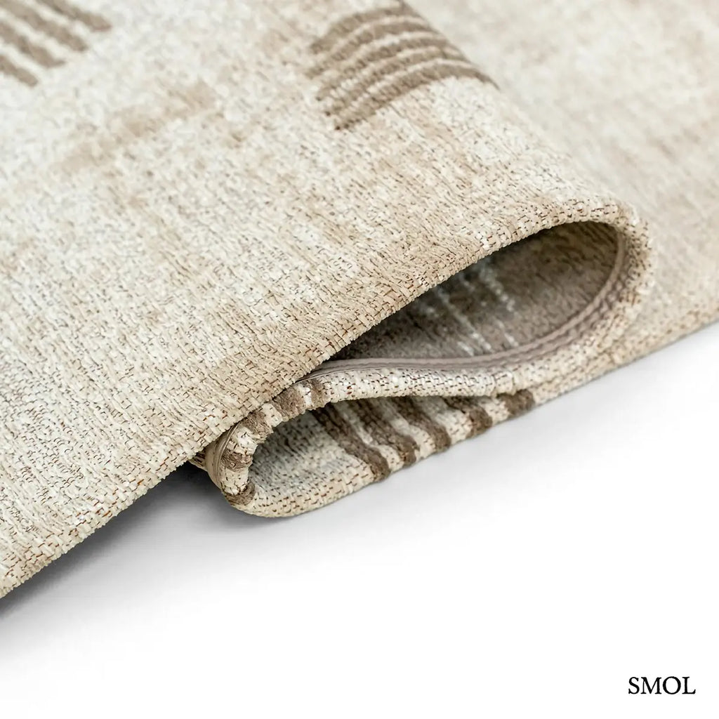 ECO RUG DUNE kalligráfia mintás szőnyeg krém alapon taupe ecsetvonásos mintával, hullámosra hajtogatva
