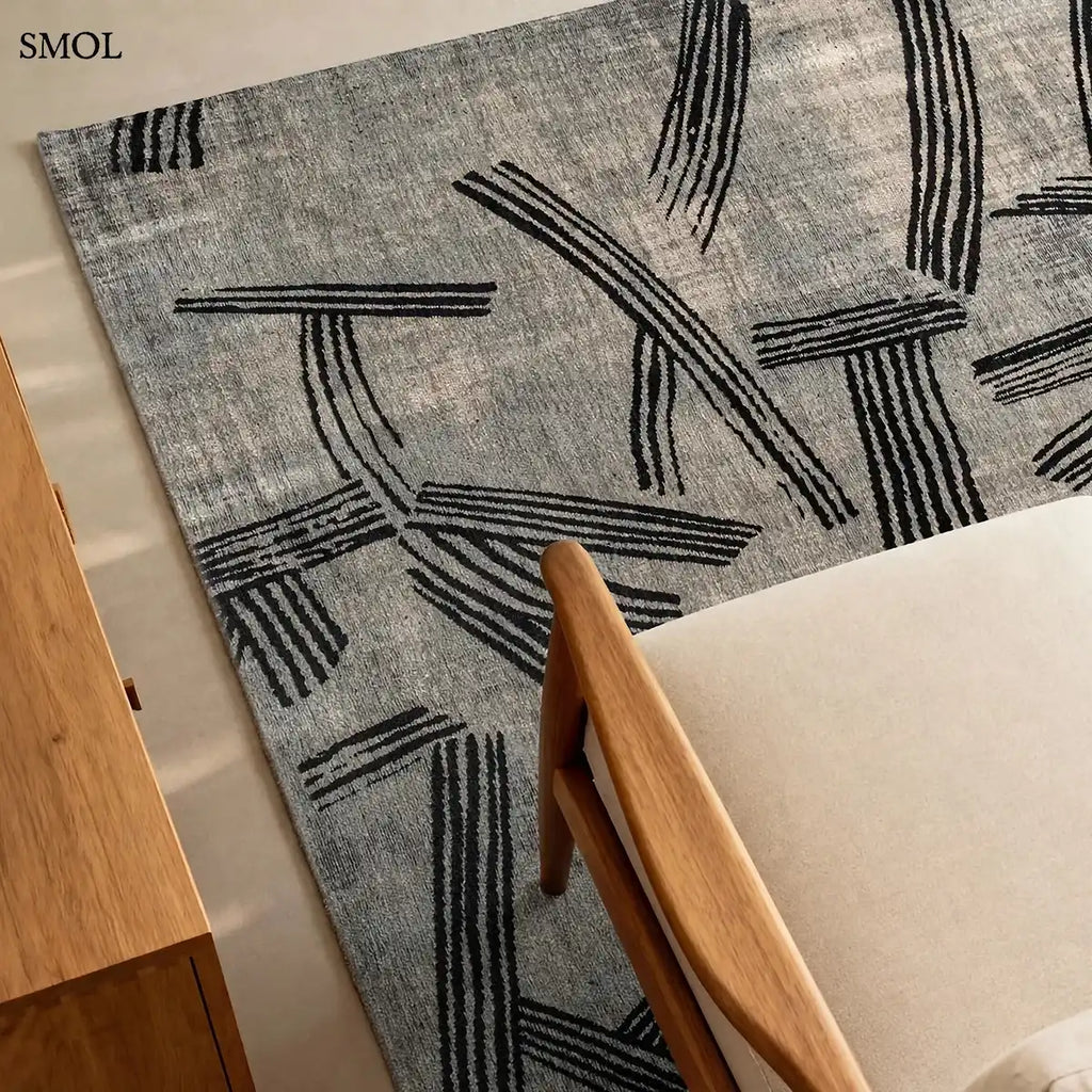 ECO RUG DARK STREET szürke-fekete kalligráfia szőnyeg japán tintavonásokkal, lapos szövés, 3 mm – kül- és beltéri, fotellel, nagyítva