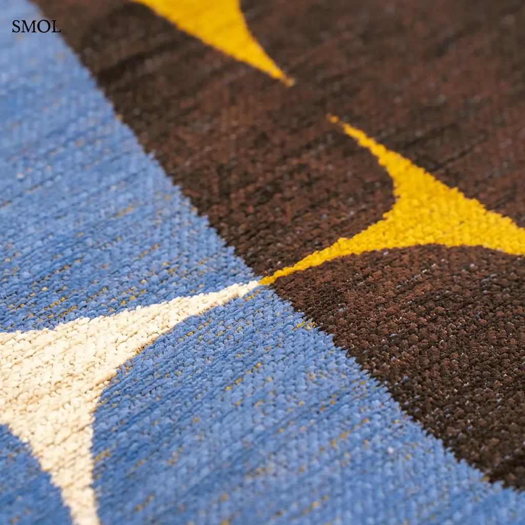 ECO RUG SUNNY BLUE szőnyeg, kék, sárga és barna kavicsszerű formákból álló, egymást átfedő mintázattal, textúra nagyítva