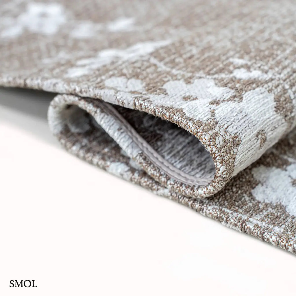 ECO RUG MORNING MIST sakura mintás szőnyeg barna-szürke alapon, fehér cseresznyevirág motívumokkal, hullámosra hajtva