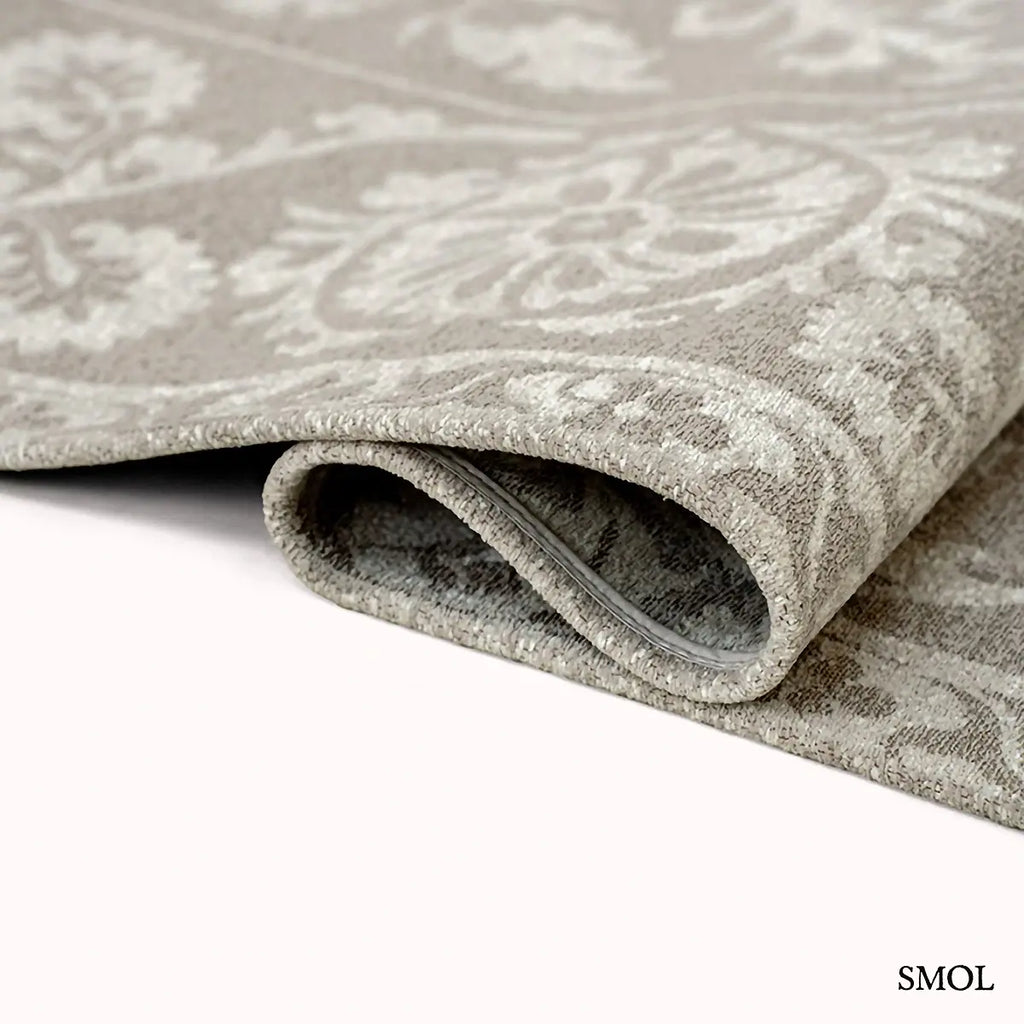 ECO RUG BOREE szőnyeg, bézs alapon szürkésbézs virágos-geometrikus suzani mintázattal, központi medállal és díszes szegéllyel, hullámosra hajtogatva